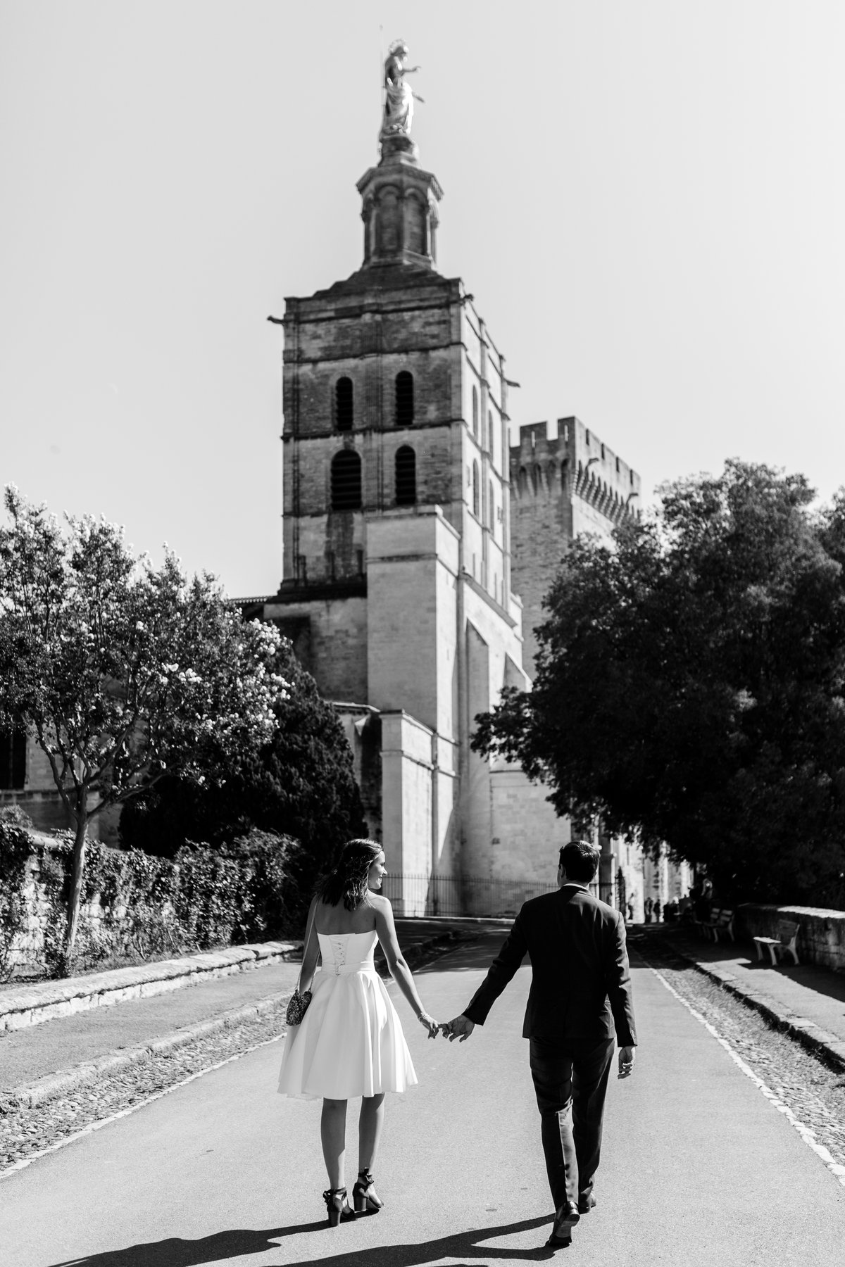 Mariés main dans la main devant un clocher, photo noir et blanc d'un mariage civil à Avignon