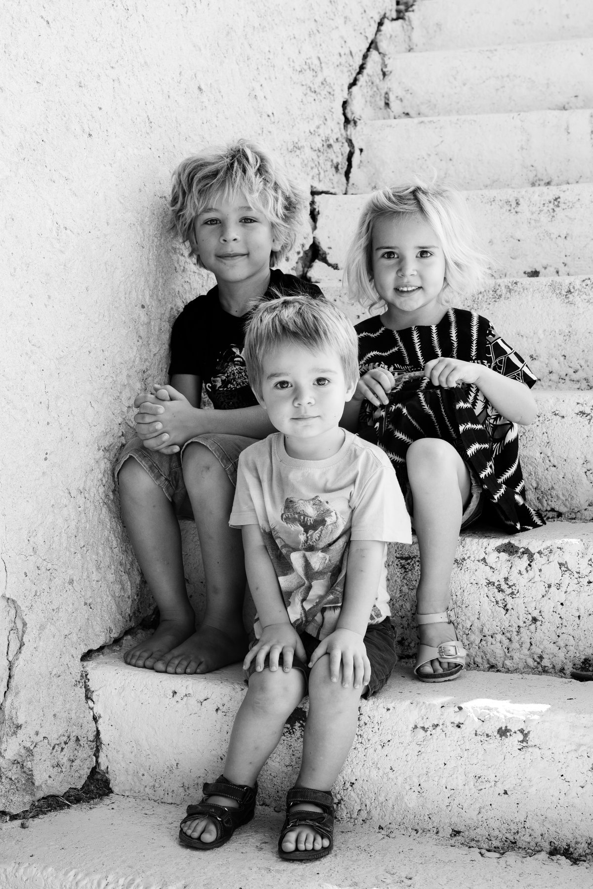 Trois enfants assis sur des marches en pierre, séance photo famille à Carpentras
