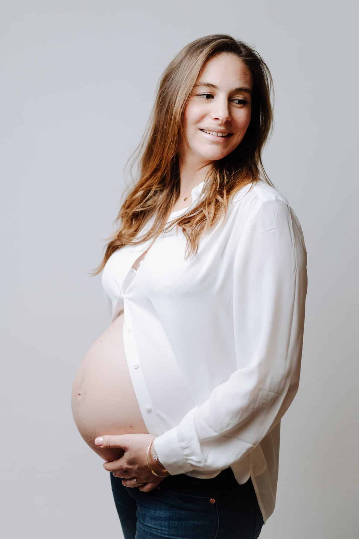 Future maman souriante, mains sur son ventre, séance photo grossesse en Avignon